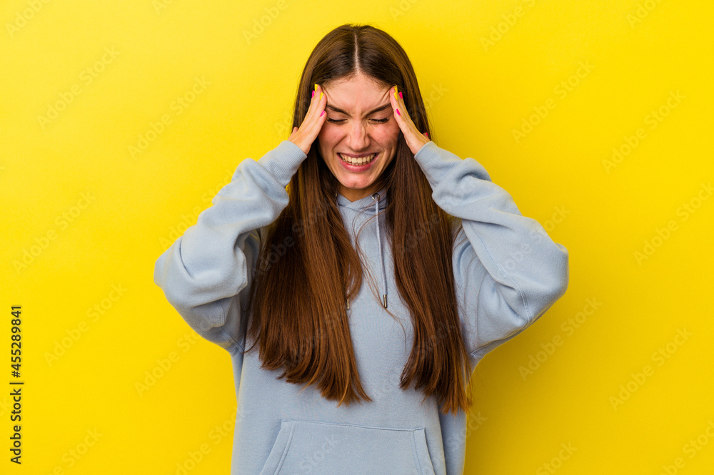 Young caucasian woman isolated on yellow background touching temples and having headache.