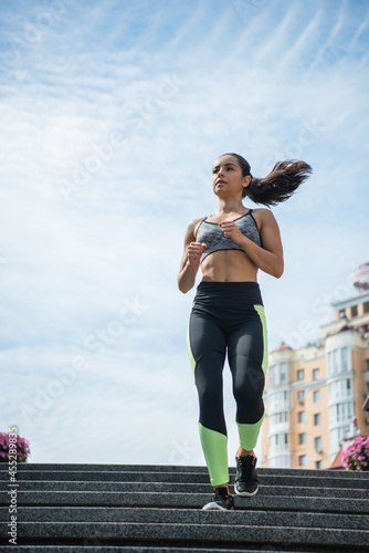 Fototapeta Naklejka Na Ścianę i Meble -  full length view of sportive woman running on urban street