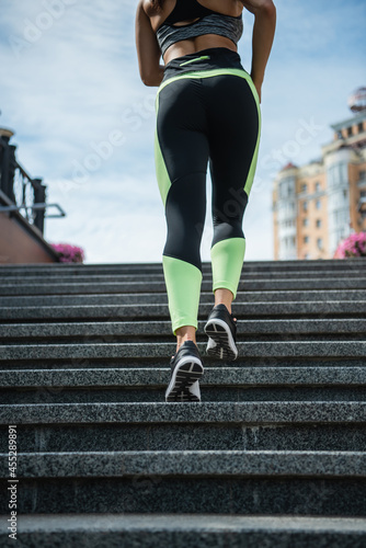 cropped view of sportive woman running on stairs outside