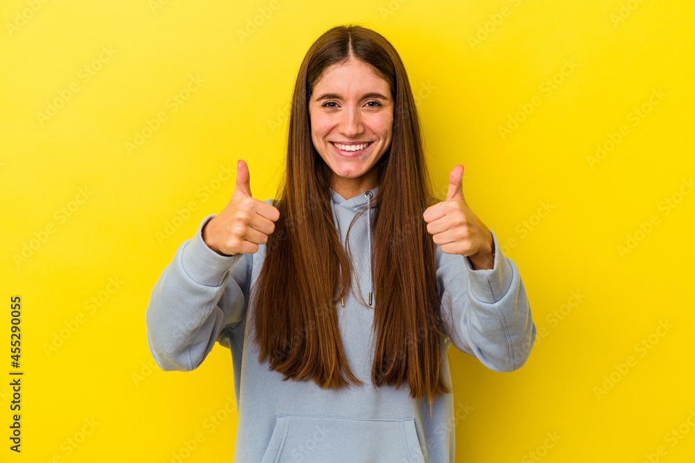 Young caucasian woman isolated on yellow background smiling and raising thumb up Young caucasian woman isolated on yellow background smiling and raising thumb up