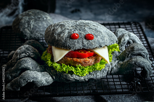Themed hamburger with spider-shaped black dough bun for the Halloween party. Halloween food concept. Horizontal.