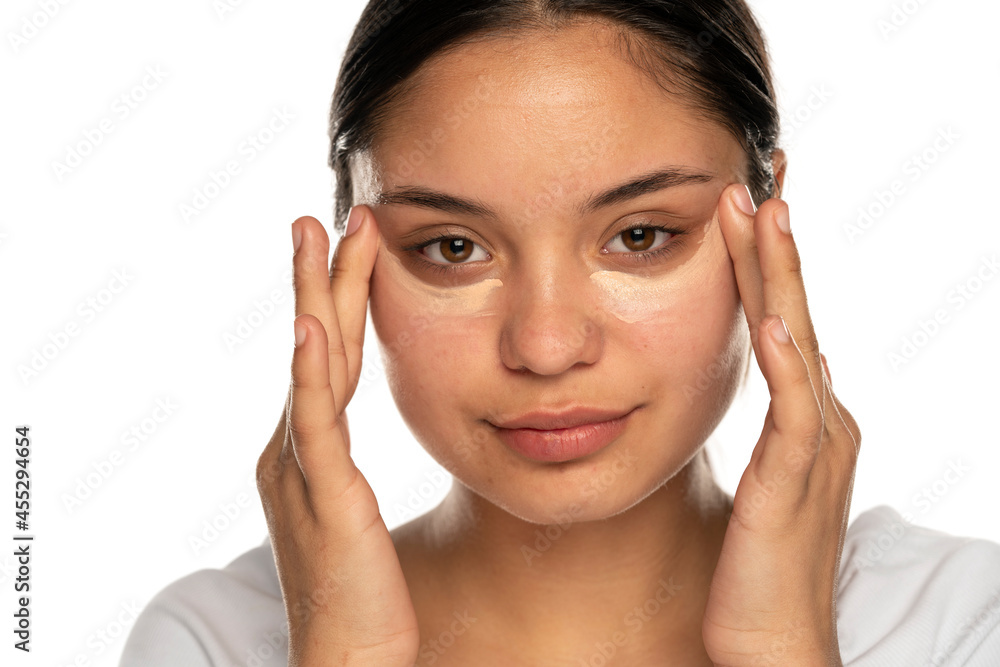 Head shot of a young beautiful woman applies concealer under her eyes Head shot of a young beautiful woman applies concealer under her eyes
