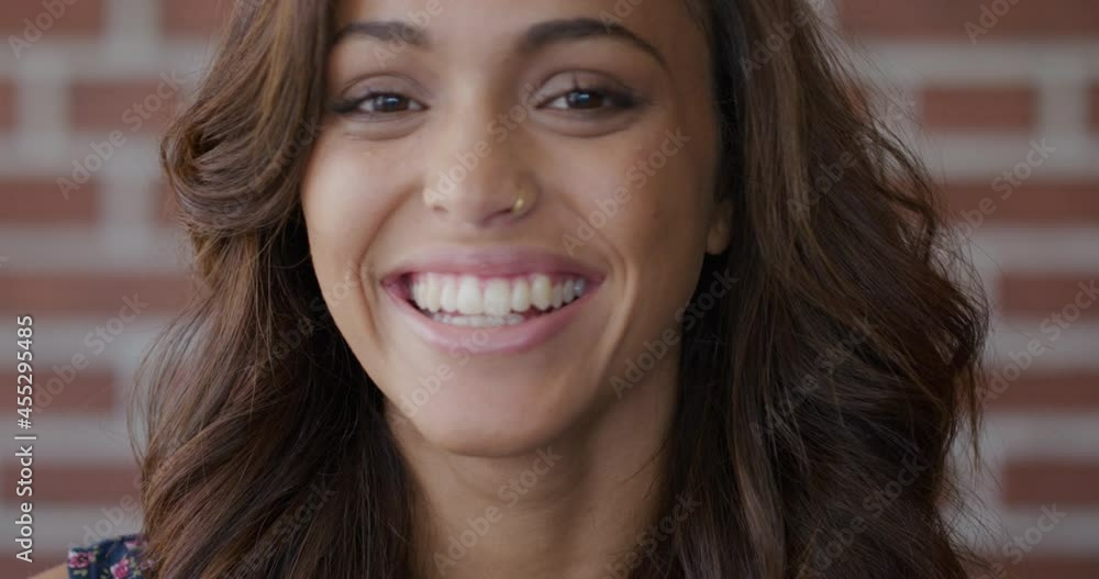 Portrait pretty mixed race woman smiling in front of brick wall Portrait pretty mixed race woman smiling in front of brick wall
