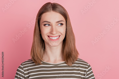 Portrait of interested funny lady look side empty space toothy smile on pink background