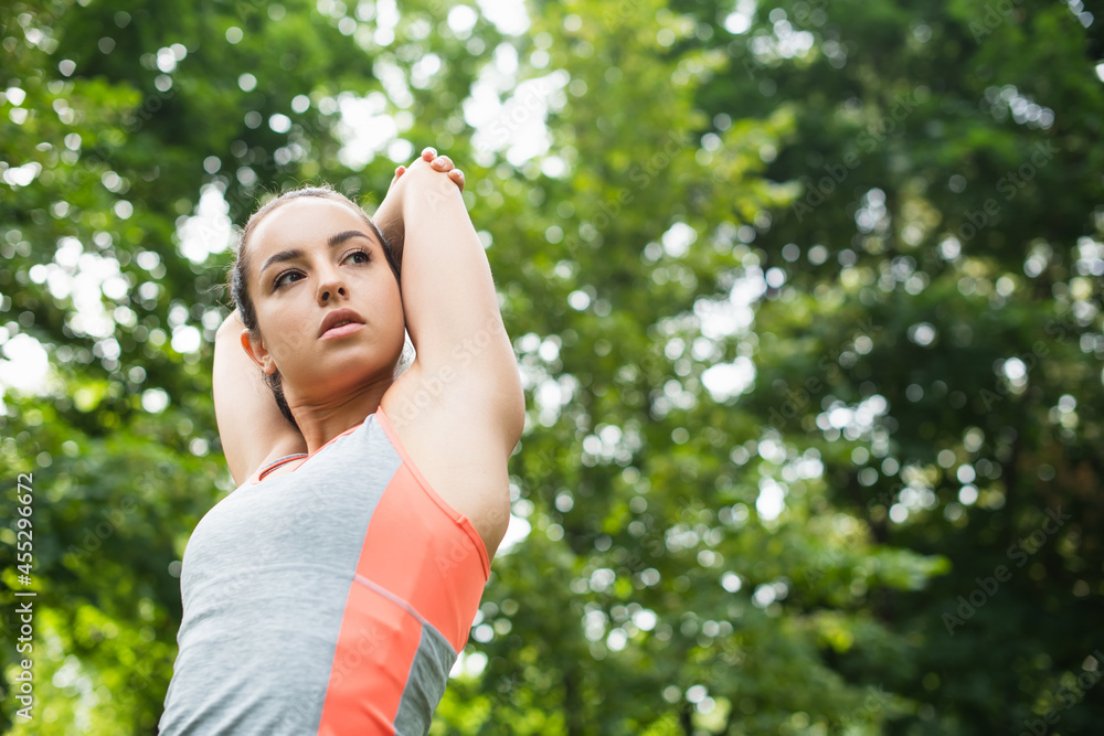 low angle view of sportive woman stretching while warming up in park low angle view of sportive woman stretching while warming up in park
