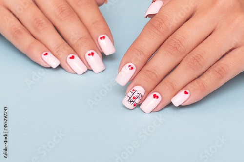 Beautiful female hands with romantic manicure nails  hearts and Valentine s day design  on blue background