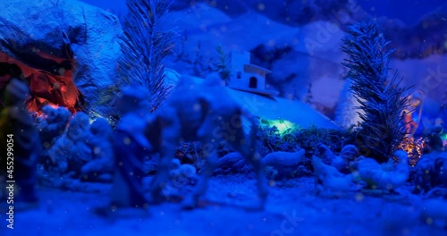 Christmas Nativity Scene with hand-coloured figures in a winter landscape. A magical night atmosphere with colored lights and falling snow. photo