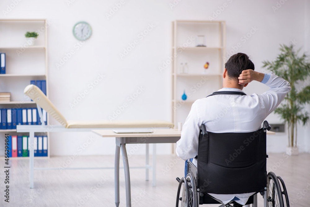 Young male doctor in wheel-chair working in the clinic Young male doctor in wheel-chair working in the clinic