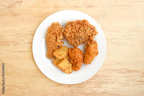 Delicious crispy fried chicken in white plate on wood background