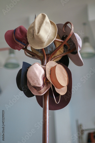 A variety of vintage colorful hats hanging on the wooden brown coat rack photo
