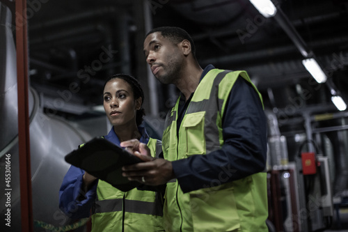 Male engineer and female engineer working together in an industrial plant room photo