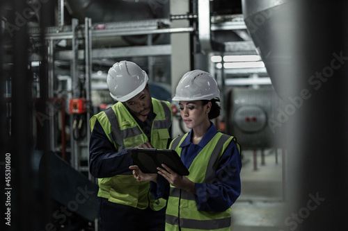 Male engineer and female engineer working together in an industrial plant room photo