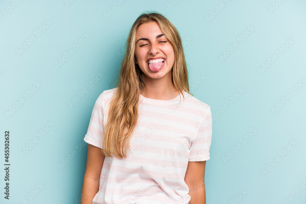 Obraz premium Young caucasian blonde woman isolated on blue background funny and friendly sticking out tongue.