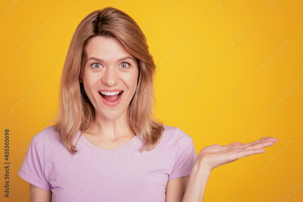 Portrait of amazed lady hand presenting blank space invisible object sale on yellow background Portrait of amazed lady hand presenting blank space invisible object sale on yellow background
