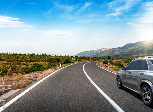 Grey car on a scenic road. Car on the road surrounded by a magnificent natural landscape. © Denis Rozhnovsky