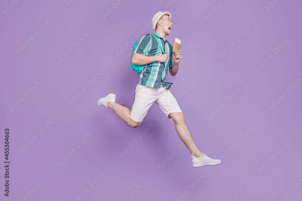 Profile portrait of crazy tourist guy jump run hold tickets visa on violet background Profile portrait of crazy tourist guy jump run hold tickets visa on violet background