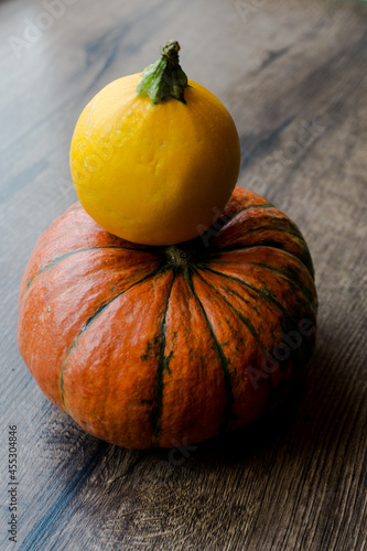Orange pumpkin and yellow round squash on a dark wooden table background.