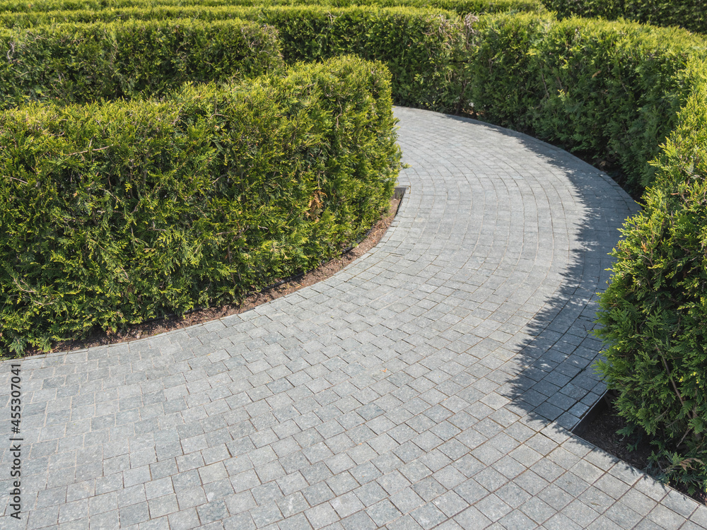 Walking path in park made in form of maze and surrounded by neatly trimmed bushes. Traditional landscaping. Walking path in park made in form of maze and surrounded by neatly trimmed bushes. Traditional landscaping.