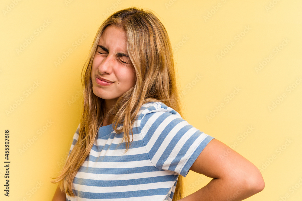 Young caucasian blonde woman isolated on yellow background suffering a back pain. Young caucasian blonde woman isolated on yellow background suffering a back pain.