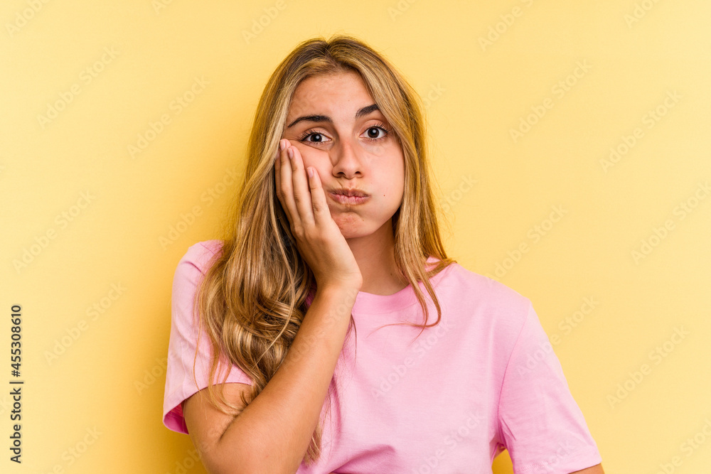 Young caucasian blonde woman isolated on yellow background blows cheeks, has tired expression. Facial expression concept. Young caucasian blonde woman isolated on yellow background blows cheeks, has tired expression. Facial expression concept.