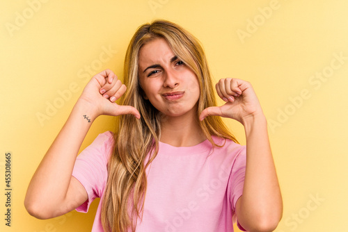 Young caucasian blonde woman isolated on yellow background showing thumb down, disappointment concept.