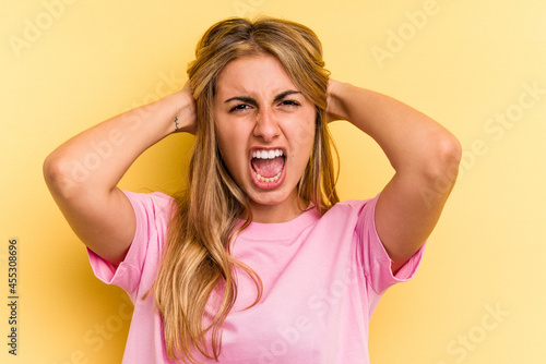 Young caucasian blonde woman isolated on yellow background screaming, very excited, passionate, satisfied with something.