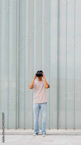 Young asian man outdoor experiencing virtual reality using 3D goggles - advertising copyspace banner