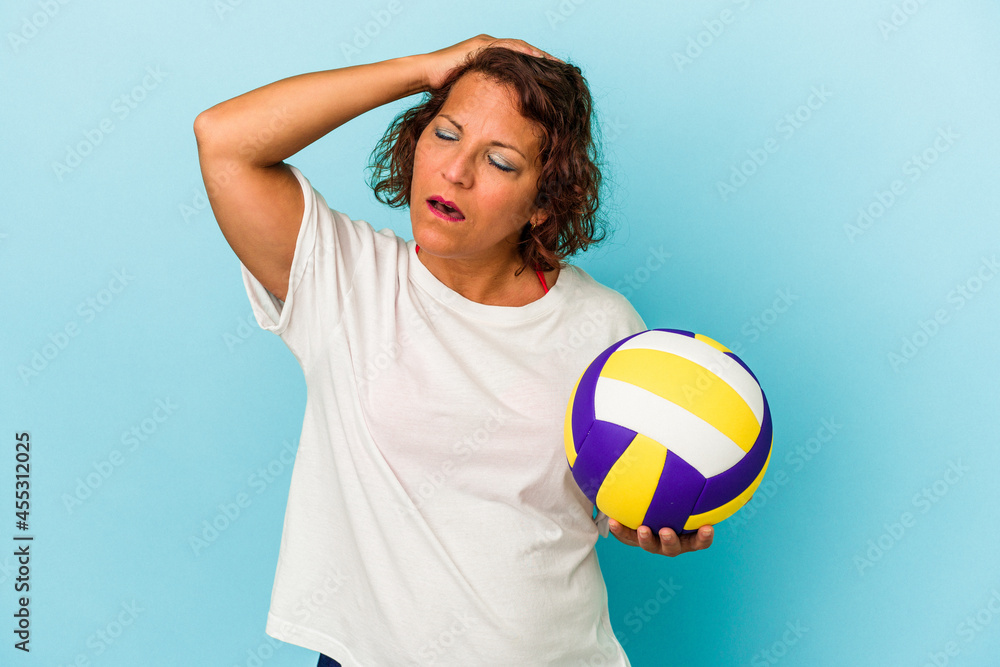 Middle age latin woman playing volleyball isolated on blue background being shocked, she has remembered important meeting.