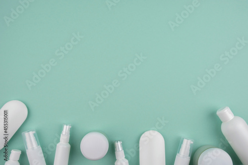 Plastic white tubes for cream or lotion bottles different sizes. Top view on light mint green background. Skincare cosmetic. Frame with place for text