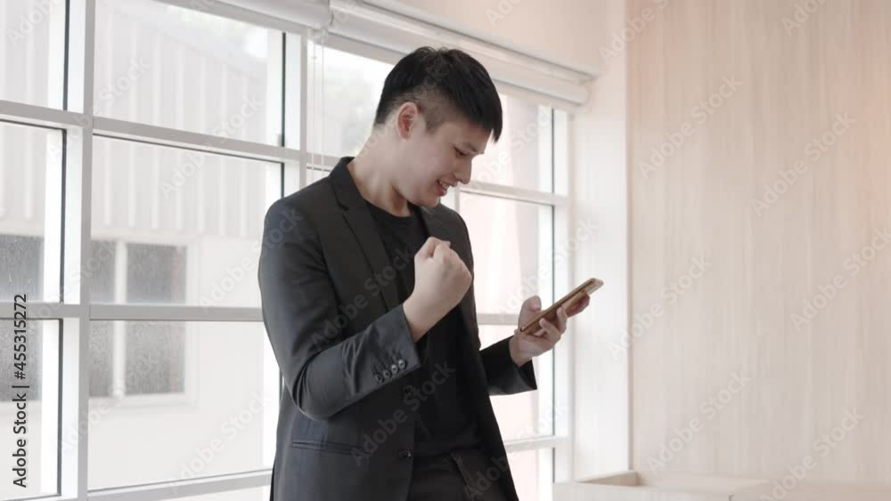 Young Asian businessman happy and exciting browsing mobile internet during office break. The salesperson is glad that receive deal from the customers. Young Asian businessman happy and exciting browsing mobile internet during office break. The salesperson is glad that receive deal from the customers.