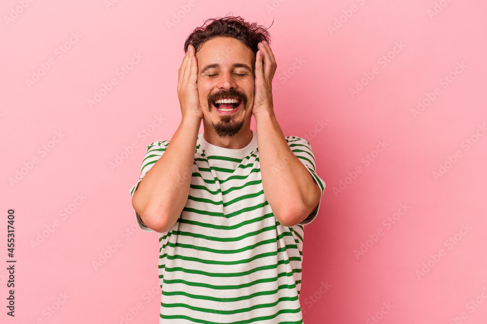 Young caucasian man isolated on pink background laughs joyfully keeping hands on head. Happiness concept. Young caucasian man isolated on pink background laughs joyfully keeping hands on head. Happiness concept.