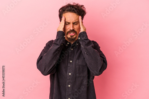 Young caucasian man isolated on pink background having a head ache, touching front of the face.