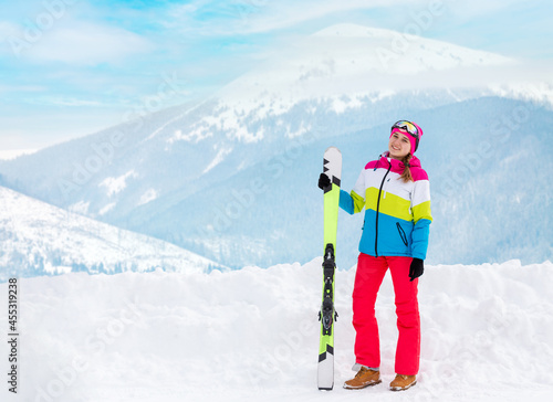 Young happy girl holding ski at mountain ski resort