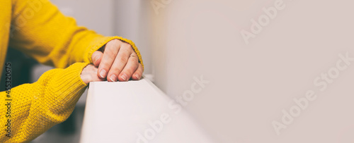 The woman warms her hands on the radiator