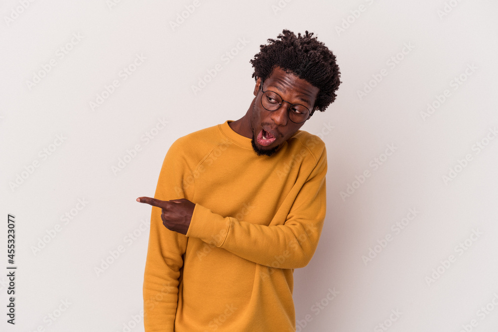 Young african american man isolated on white background points with thumb finger away, laughing and carefree. Young african american man isolated on white background points with thumb finger away, laughing and carefree.
