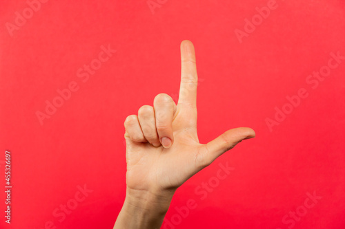 Letra L en lenguaje de señas. Fondo rojo.