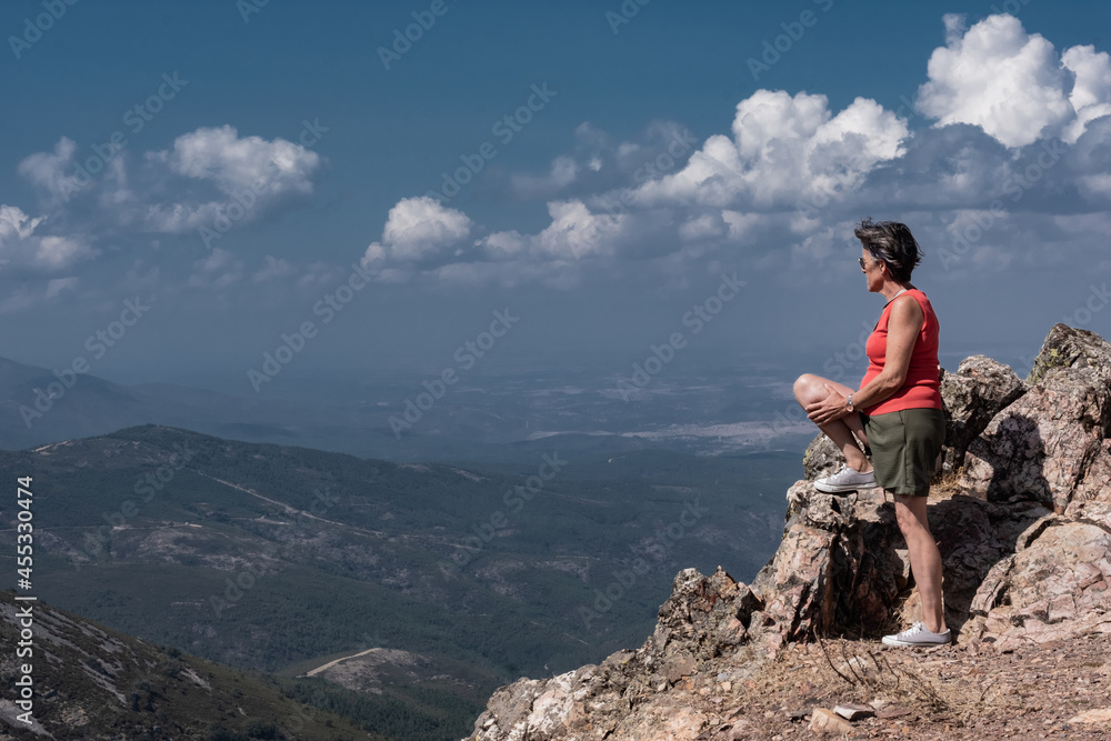 Woman looking down on the valley from a mountain top