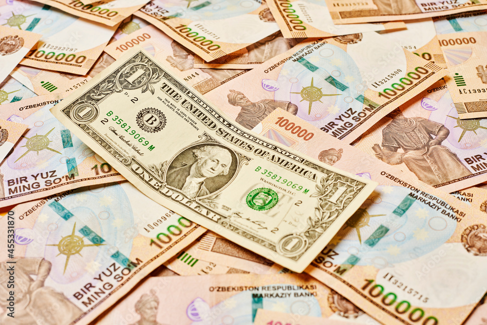 US dollar banknote and Uzbek sums. Concept of exchange rate, Uzbek sum to us dollar. Money exchange in Uzbekistan. Pile of Uzbek money sum and American dollar bill US dollar banknote and Uzbek sums. Concept of exchange rate, Uzbek sum to us dollar. Money exchange in Uzbekistan. Pile of Uzbek money sum and American dollar bill