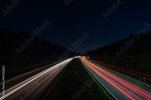 Lighttrails of a traffic motorway from the cars front and headlights, passing fast the point ov view.