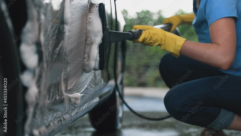 Woman in uniform cleaning car with brush. Car wash service. Woman in uniform cleaning car with brush. Car wash service.