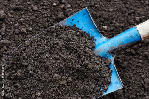 Soil on blue color shovel in soil background, sustainable agriculture and gardening concept 