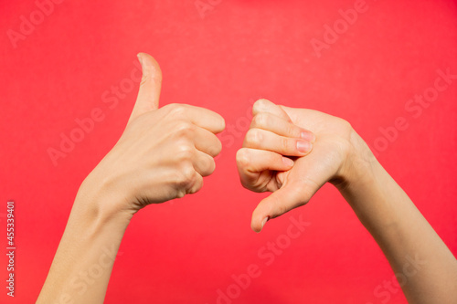 Manos pulgar arriba y abajo. Fondo rojo 