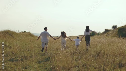 Parents with playful kids running toogether on nature photo