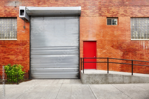 Empty street with brick wall building with automatic rolling shutter, New York, USA.