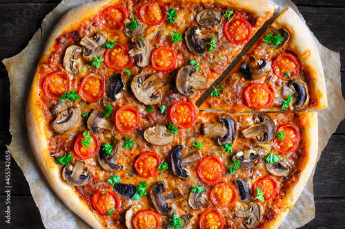 Vegan mushrooms pizza with cherry tomatoes and dairy free mozzarella cheese on a rustic wooden background. Clean eating, plant based food concept. Top view