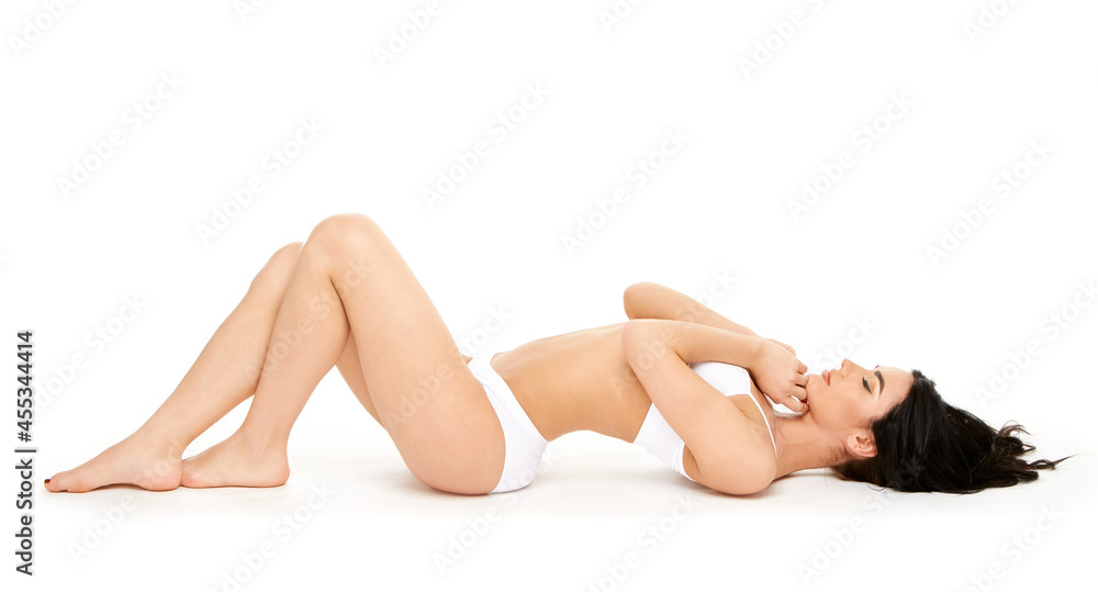 Fitness young woman with a beautiful body sitting on white background