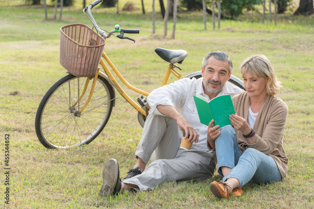 Senior couple relax sitting and reading book together at the park. leisure activity on weekend