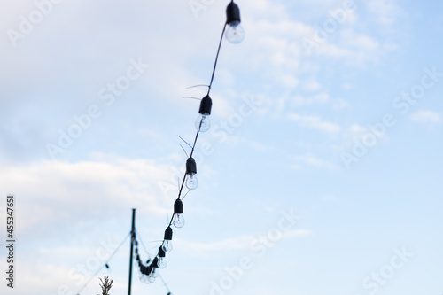 Lamps in series with the blue sky background . Street electric garland against the sky. One row of street lights for lighting