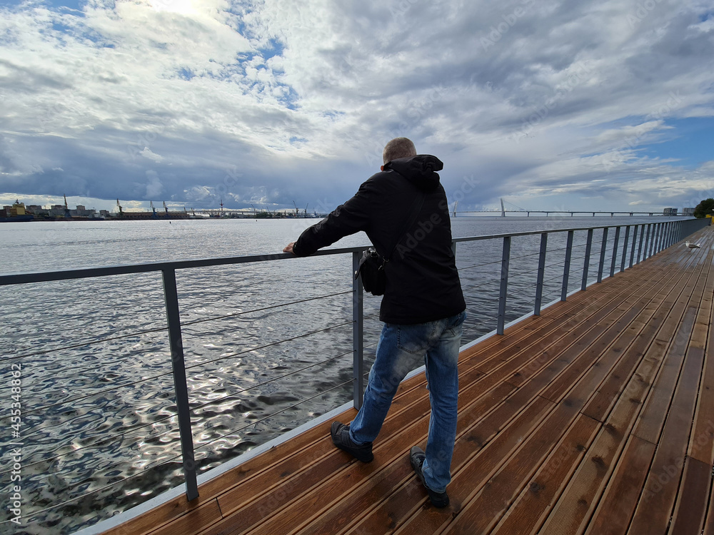 A man on a bridge in St. Petersburg. A mature man walks in the city by the water.