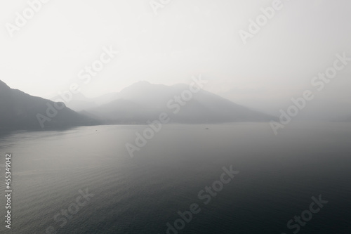 Black and white photo with a foggy mountains in Como lake. Hazy and misty lake view © Audrius